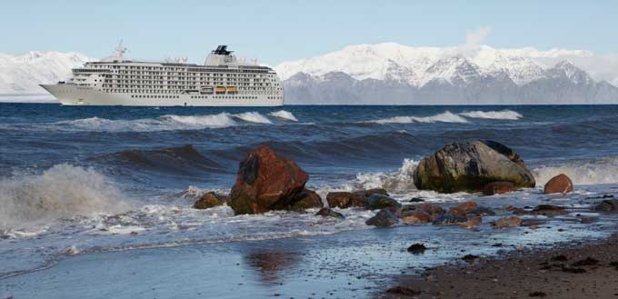 The luxury ship MV THE WORLD at anchor in blue seas with moutains beyond, after having crossed the Northwest Passage from the Pacific. Photo by Pat and Rosemarie Keough